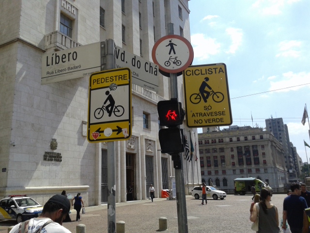 Placas de trânsito indicando preferência de pedestres e ciclistas no centro de São Paulo