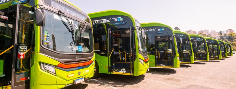 A foto mostra a frente de 8 ônibus elétricos enfileirados lado a lado
