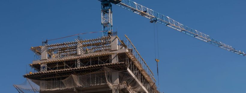 Imagem de topo de prédio sendo construído, com céu azul no fundo