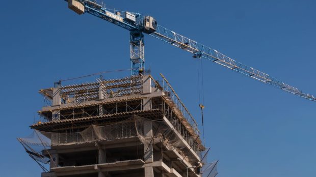 Imagem de topo de prédio sendo construído, com céu azul no fundo